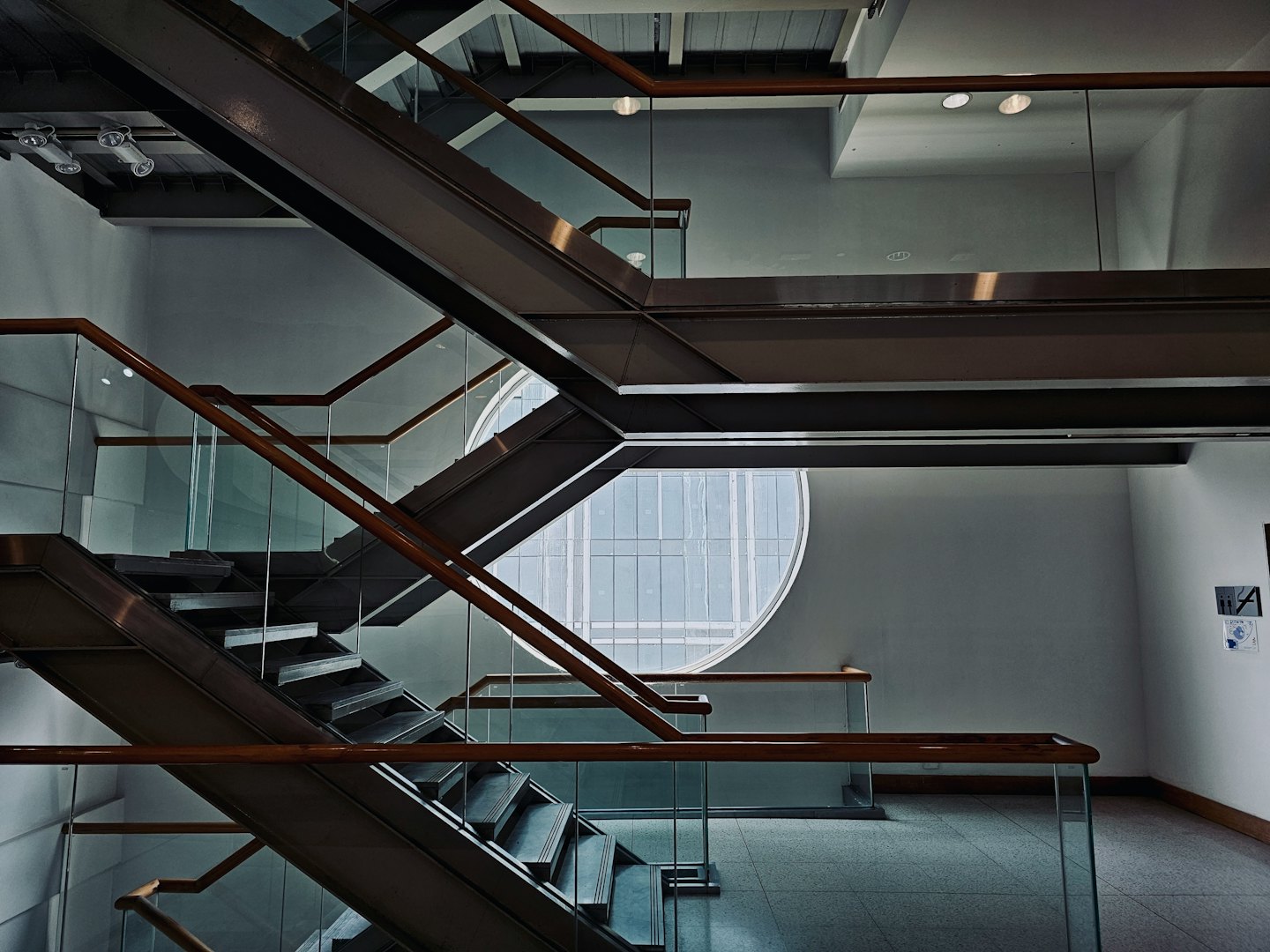 Escaleras industriales de metal con barandillas de cristal en un edificio moderno.