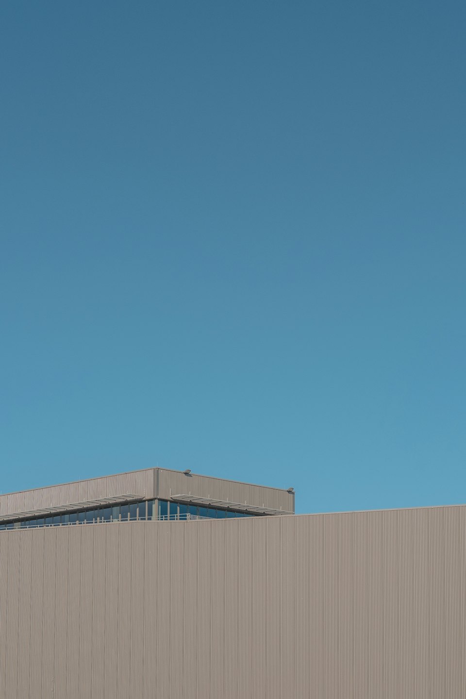 Edificio industrial moderno con revestimiento de metal corrugado bajo cielo azul.