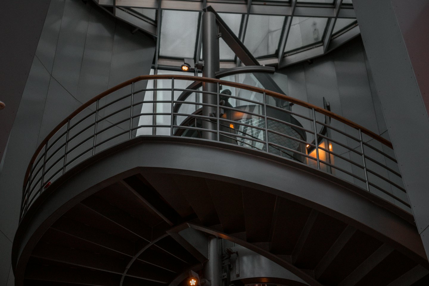 Escalera de caracol moderna con pasamanos de madera dentro de un edificio de cristal.