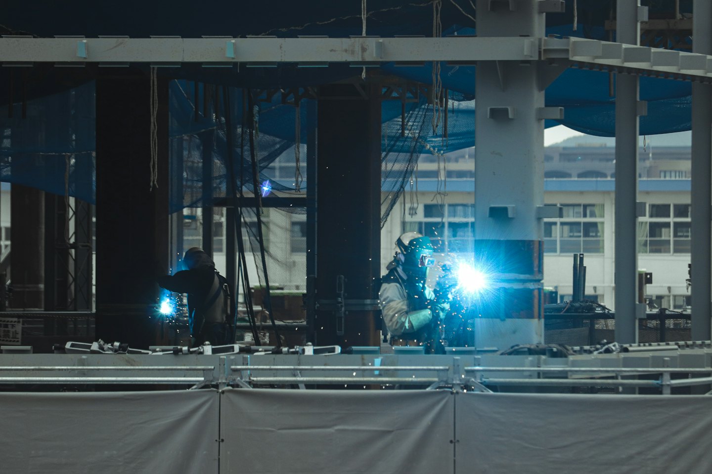 Obreros de la construcción sueldan estructuras de acero con chispas azul brillante.