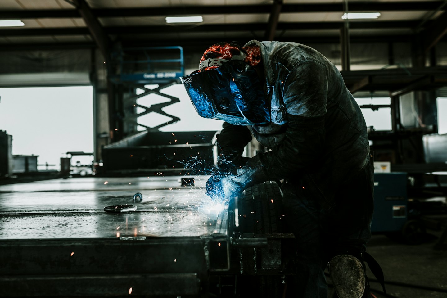 Soldador con casco y guantes trabajando en una estructura metálica.